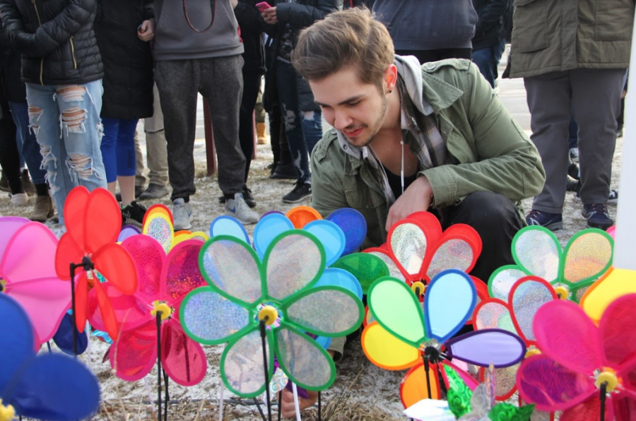 Senior Holden Mikesell places a pinwheel in the ground to honor the lives of the 17 students and teachers lost in the Parkland shooting on February 14. 