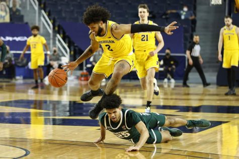 Isaiah Livers of the Michigan Wolverines pursues a loose ball against Malik Hall of the Michigan State Spartans.